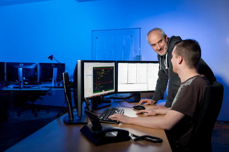 HPS -2 employees are consulting in front of a computer workstation