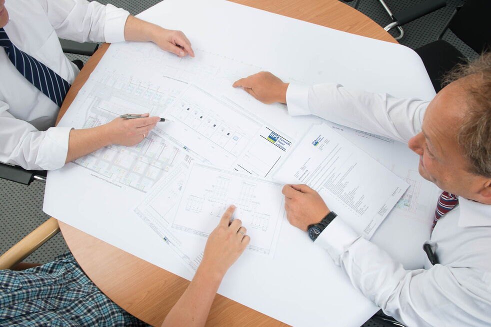 Mann sitzt vor 3 Computerdisplays